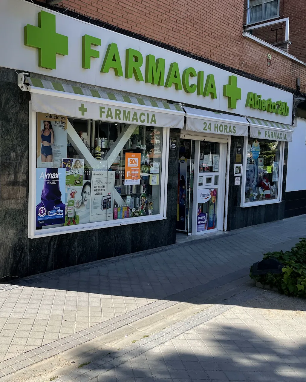 Fachada de la farmacia en la esquina de la Avenida de la ONU, con su rótulo verde y el toldo de 24 horas