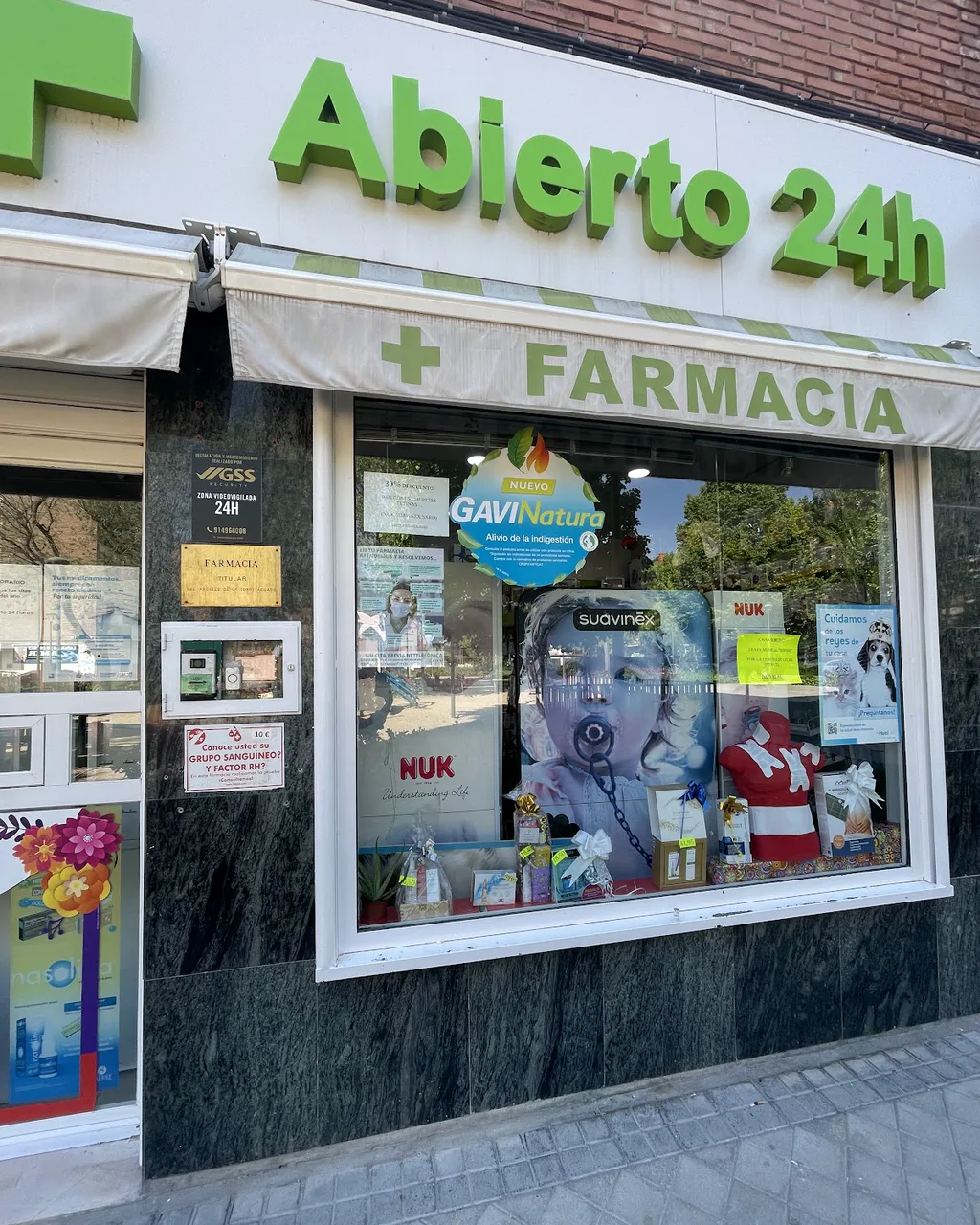 Rótulo de abierto 24 horas sobre el escaparate de la farmacia