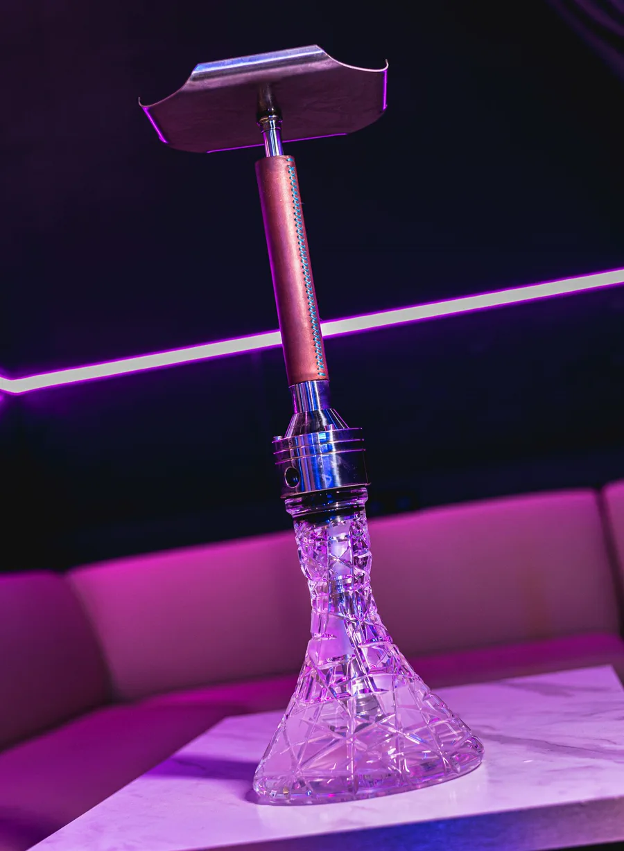 Cachimba VZ Pandora Leather Hookah con tubo de piel sobre una mesa con luz rosa
