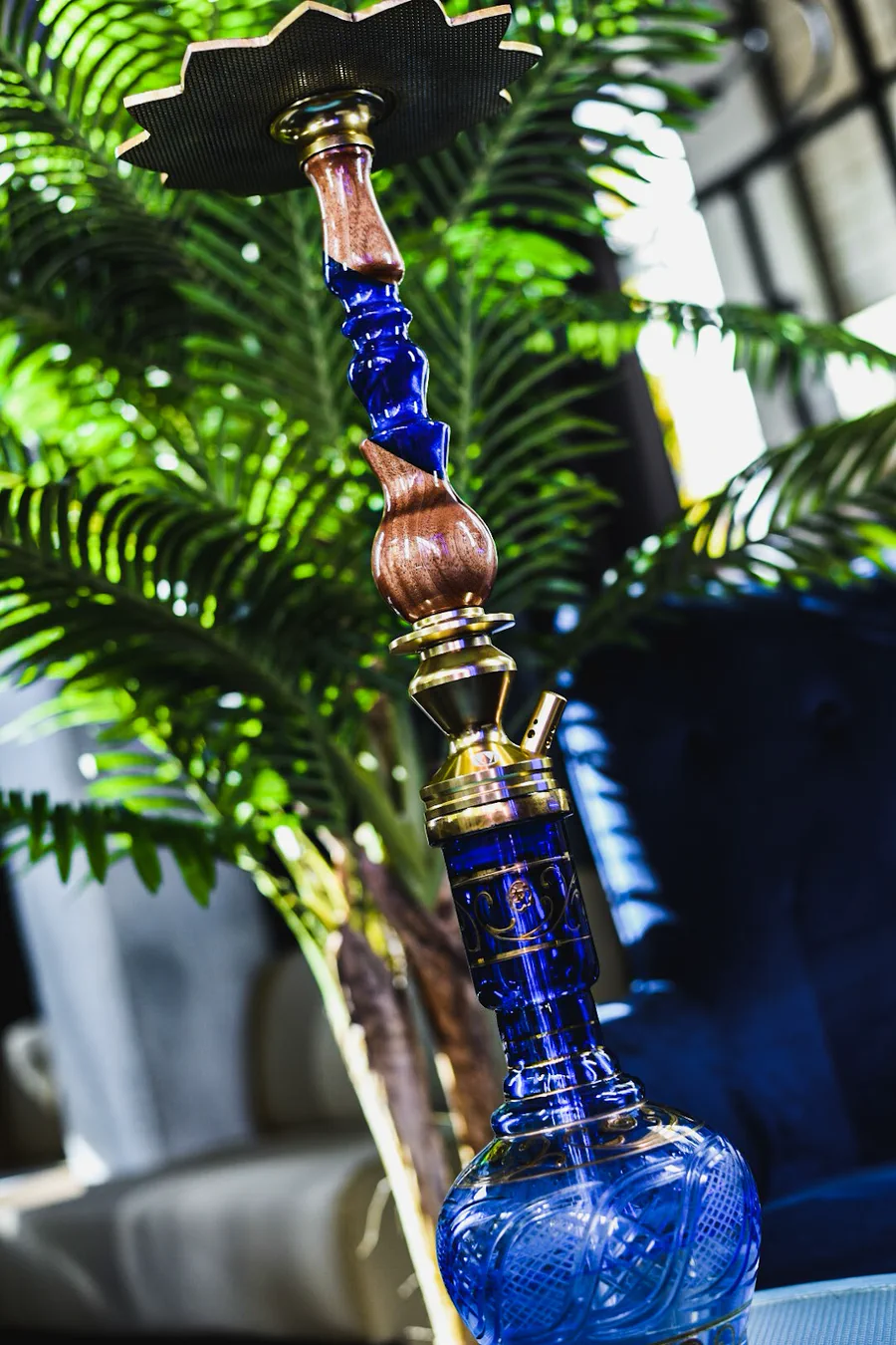 Cachimba de cristal azul y madera junto a una palmera