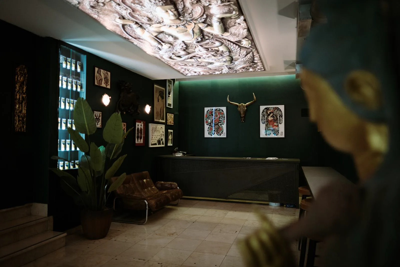 Sala de espera con paredes verde oscuro, plantas y diseños enmarcados