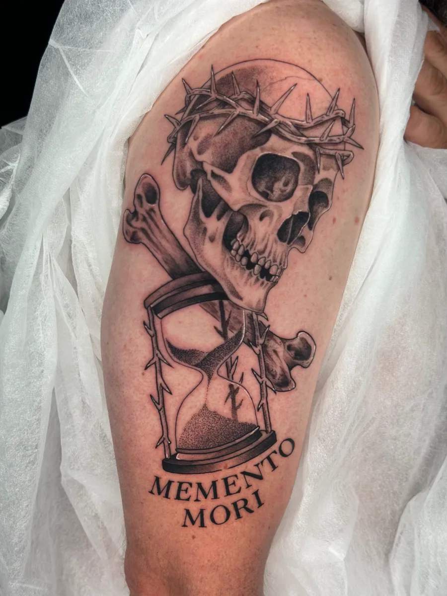 Calavera con reloj de arena y la frase Memento mori, tatuada en el brazo